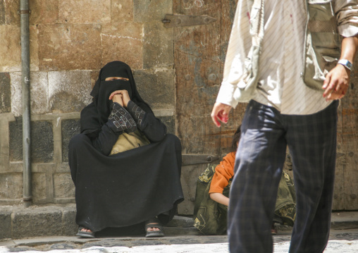Yemeni woman with burqa sit in the street, Amanat Al-Asemah, Sanaa, Yemen