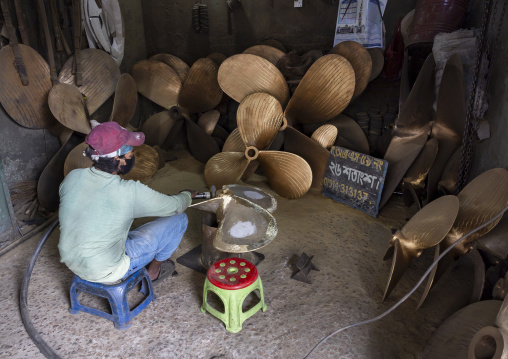 Bangladeshi dockyard worker polishing a propeller, Dhaka Division, Keraniganj, Bangladesh