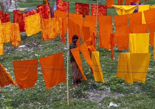 Bangladeshi worker hanging orange fabrics under the sun, Dhaka Division, Rupganj, Bangladesh