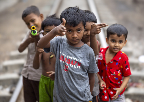 Bangladeshi boy miming guns with hands along a railway track, Chittagong Division, Chittagong, Bangladesh