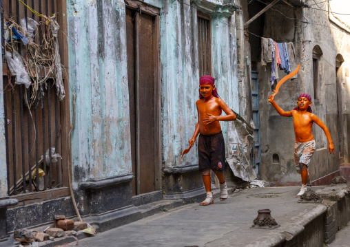 Young hindu devotees in orange color playing with swords at Lal Kach festival, Dhaka Division, Munshiganj, Bangladesh