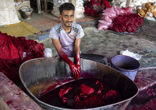Bangladeshi man dyeing fabrics in red in a batik factory, Chittagong Division, Comilla, Bangladesh