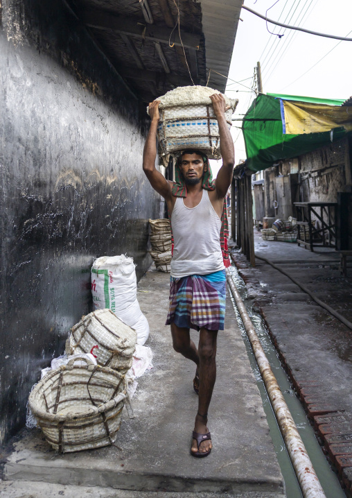 Bangladeshi man weighing basket with salt at a factory, Chittagong Division, Chittagong, Bangladesh
