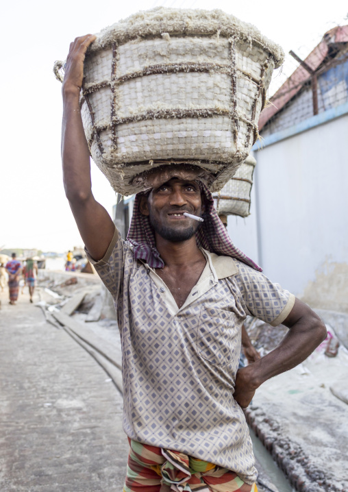 Bangladeshi man weighing basket with salt at a factory, Chittagong Division, Chittagong, Bangladesh