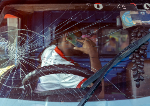 Man calling on the phone behind a shattered windshield, Chittagong Division, Chittagong, Bangladesh