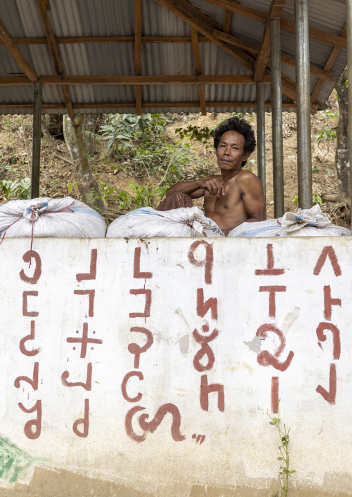 Murong ethnic group man above a mural with local alphabet, Chittagong Division, Bandarban, Bangladesh