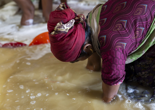 Bangladeshi woman washing salt in water in a factory, Chittagong Division, Chittagong, Bangladesh