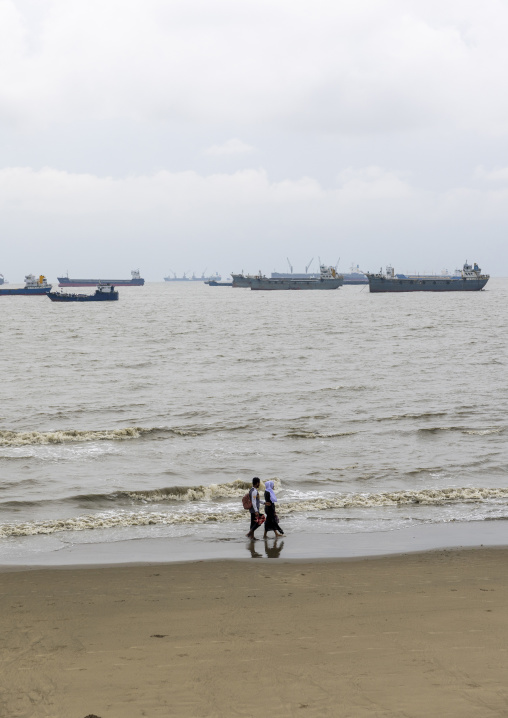 Couple walking on the beach with tanker ships in the back, Chittagong Division, Chittagong, Bangladesh