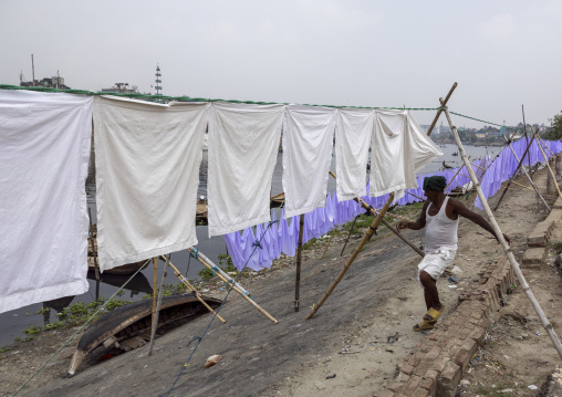 Man taking off household linens hanging on clothesline, Dhaka Division, Keraniganj, Bangladesh