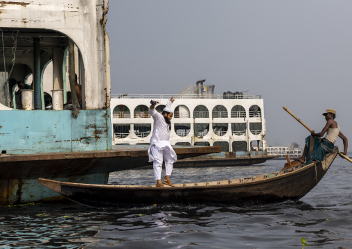Muslim man jumping from on a ferry vessel into a small boat, Dhaka Division, Keraniganj, Bangladesh