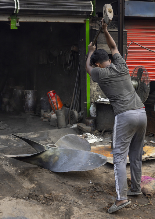 Bangladeshi worker breaking a propeller at Dhaka shipyard, Dhaka Division, Keraniganj, Bangladesh