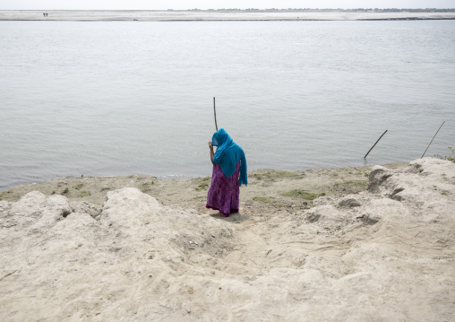 Bangladeshi woamn on a sandy riverbank, Dhaka Division, Shivalaya, Bangladesh