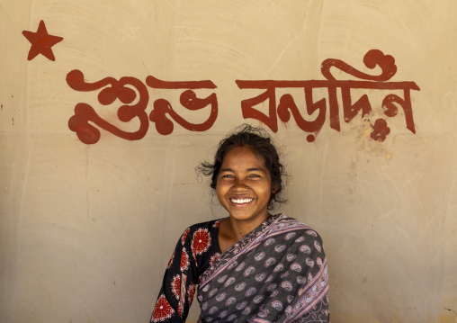 Christian girl from Santal ethnic group below Merry Christmas on the wall, Rajshahi Division, Tanore, Bangladesh