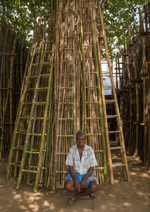 Old indian man sitting in front of wooden ladders, Tamil Nadu, Madurai, India