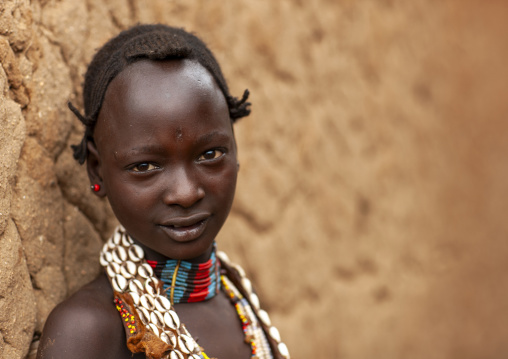 Portrait of a Hamer girl in front of clay house, Omo valley, Turmi, Ethiopia