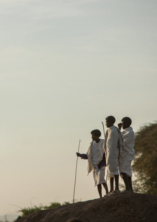 Three Karrayyu tribe men standing on top of a hill, Oromia, Metehara, Ethiopia