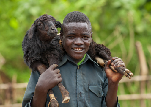 Man carrying a sheep on his shoulders, Omo valley, Tum, Ethiopia