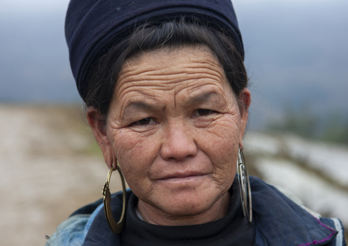 Smiling old black Hmong woman with hat and earrings, Lao Cai province, Sapa, Vietnam