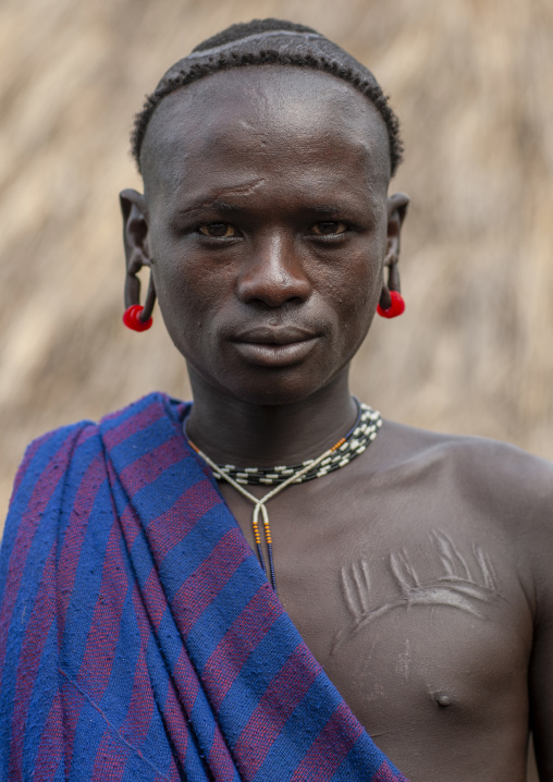 Surma tribe man with enlarged ear and scarifications, Omo valley, Tulgit, Ethiopia