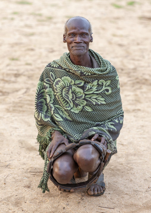 Portrait of a Karo tribe man wrapped up in a cover and squatting, Korcho, Omo valley, Ethiopia
