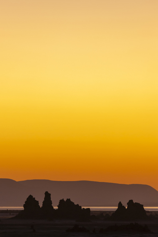 Limestone chimneys stand silhouetted against a vivid orange sunset sky, Afar depression, Lake Abbe, Djibouti