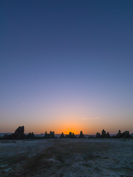 The sun sets behind limestone chimney rock formations on the horizon, Afar depression, Lake Abbe, Djibouti