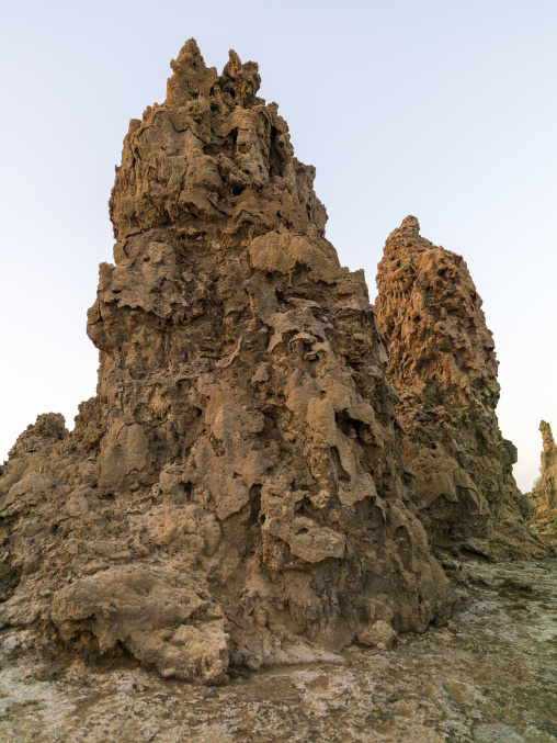 A jagged limestone chimney rock formation towers against a pale sky, Afar depression, Lake Abbe, Djibouti