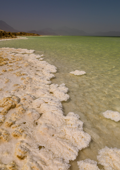 Thick white salt crusts form along the shore of a turquoise crater lake, Dikhil Region, Lake Assal, Djibouti