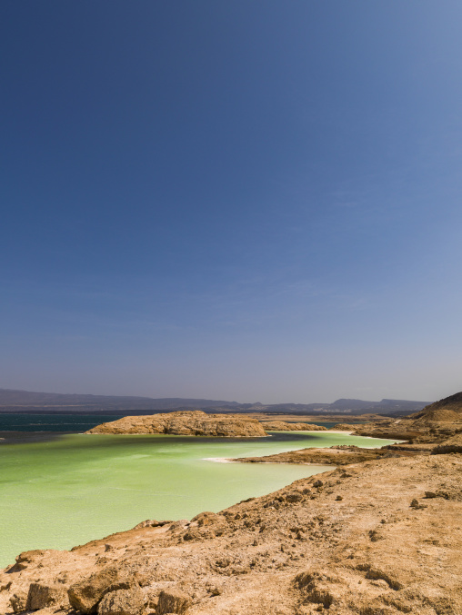 A sandy rocky peninsula divides the turquoise waters of the crater lake, Dikhil Region, Lake Assal, Djibouti