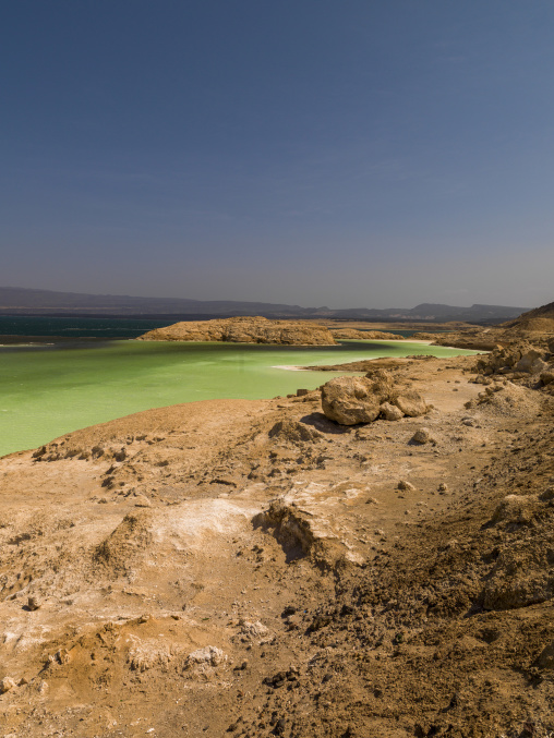 Turquoise green waters of Lake Assal meet a barren volcanic shoreline, Dikhil Region, Lake Assal, Djibouti