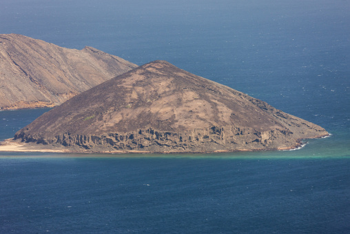 A pyramid-shaped volcanic peak overlooks a narrow beach at the Devil's Cauldron, Tadjourah Region, Goubet Al-kharab, Djibouti