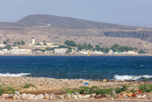 The coastal town of Tadjoura spreads along the shoreline beneath desert hills and dark cliffs, Tadjourah Region, Tadjoura, Djibouti