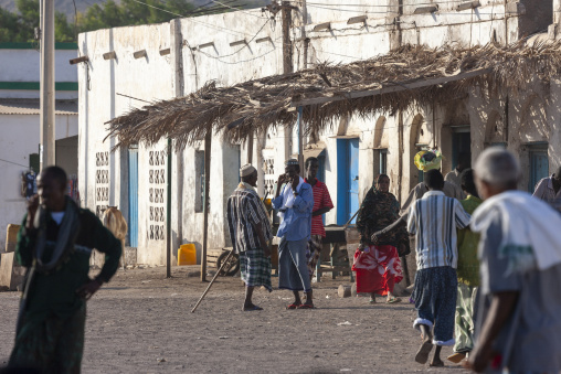 Villagers gather beneath a palm-thatched awning outside whitewashed buildings in a market street, Tadjourah Region, Tadjoura, Djibouti