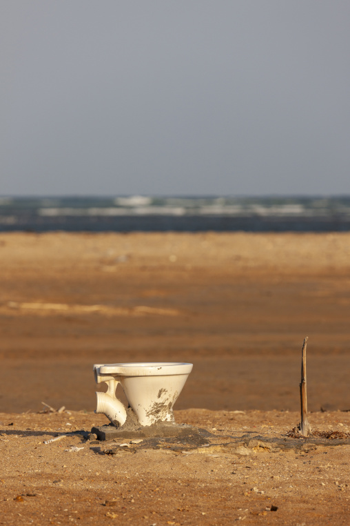 A broken toilet lies abandoned on a sandy beach, Obock Region, Gorodia, Djibouti