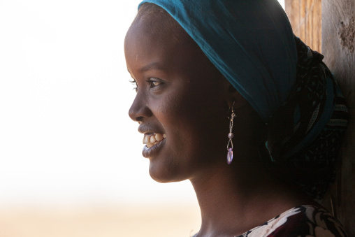 Young afar woman in a teal headscarf smiles in profile, Obock Region, Khor angar, Djibouti