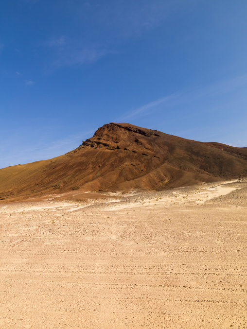A solitary volcanic hill dominates a barren desert plain, Obock Region, Khor angar, Djibouti