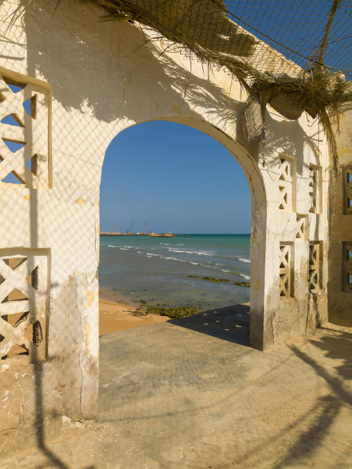 The archway of a restaurant destroyed in the civil war opens onto a construction site by the sea, Obock Region, Obock, Djibouti