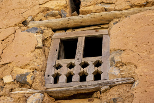 Close-up of a carved wooden window lattice screen set into a crumbling mudbrick wall, Ad Dakhiliyah Region, Al Hamra, Oman