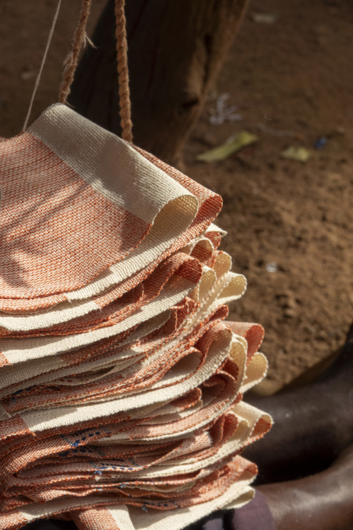 Folded Senufo cotton cloths hang on cords ready for sale at a street market, Savanes district, Waraniene, Ivory Coast