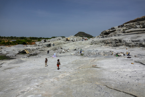 Two children stand on the flat granite bed of an open-air quarry, Savanes district, Shienlow, Ivory Coast