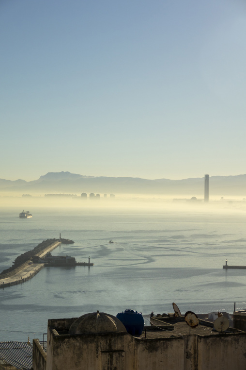 Misty morning view over Algiers harbor with breakwater lighthouse and cargo ship, North Africa, Algiers, Algeria