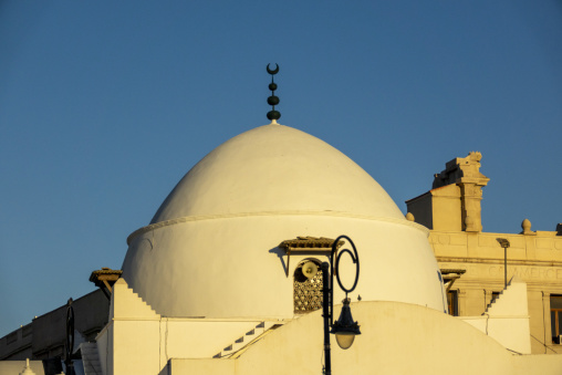 White dome and crescent finial of a historic mosque beside the old Chamber of Commerce building, North Africa, Algiers, Algeria