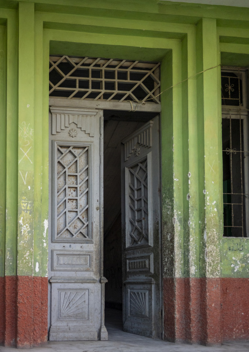 Ornate wooden double door with a lattice transom set into a green colonial building facade, Namibe Province, Namibe, Angola