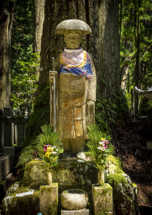 Stone Jizo pilgrim statue wearing a straw hat and colorful bib d