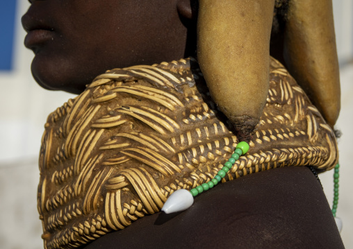 Profile close-up of a Mwila woman's ochre hair roll draped over a woven shoulder covering decorated with cowrie shells, Huila Province, Lubango, Angola