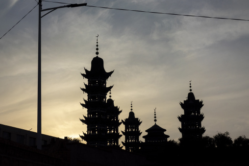 Chinese-style minarets of the Salar people's grand mosque stand silhouetted at dusk, Qinghai Province, Xunhua, China