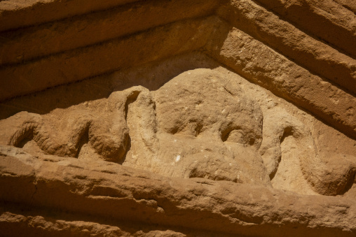 Weathered face carving with a serpent behind it on a Nabataean t