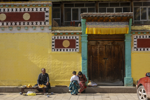 Tibetan family and street vendor outside a building at Wutun si monastery, Qinghai Province, Wutun, China