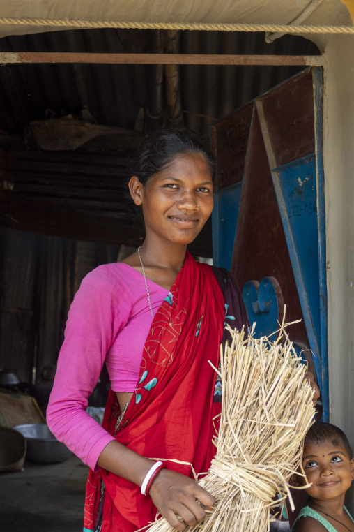 Portrait of a smiling young woman carrying straw with a child ne