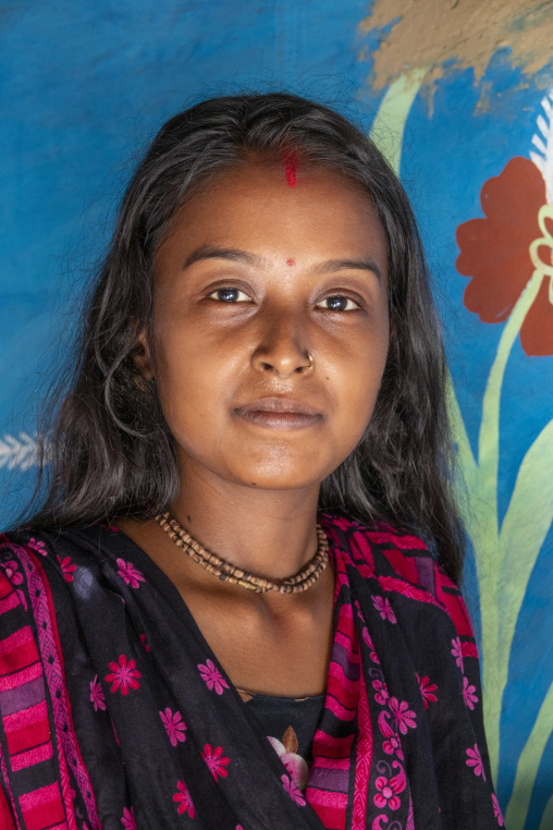 Portrait of a young woman with a red tika against a blue painted